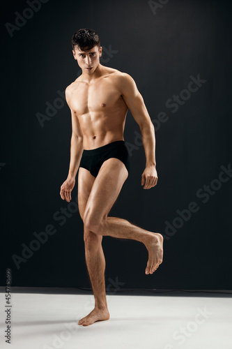 sporty man in black shorts with a pumped body on a dark background model