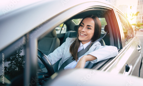 Portrait of cute female driver steering car with safety belt