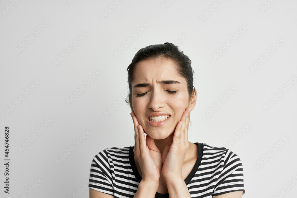 woman in striped t-shirt holding face dentistry discomfort pain woman in striped t-shirt holding face dentistry discomfort pain