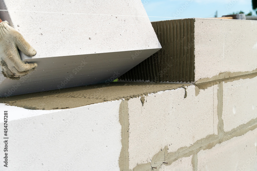 Builder makes a concrete wall with cement blocks on the construction site of a house. Concept of building a house Builder makes a concrete wall with cement blocks on the construction site of a house. Concept of building a house