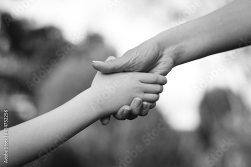Parent holds the hand of a child on a walk. Kid and mother hands, closeup. Love, relationship and teamwork in family.