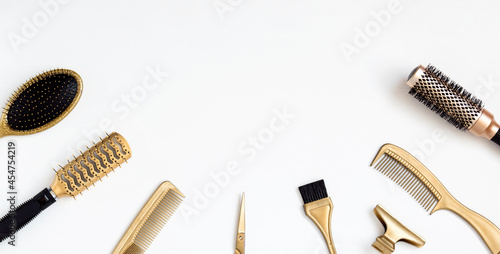 Golden hairdresser tools on a white background, scissors, comb, clip, brush. Hair salon accessories, template with space for text.