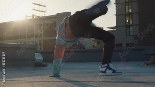 dancing man breakdancing on roof top hip hop dancer practicing dance routine performing freestyle moves in city at sunset photo