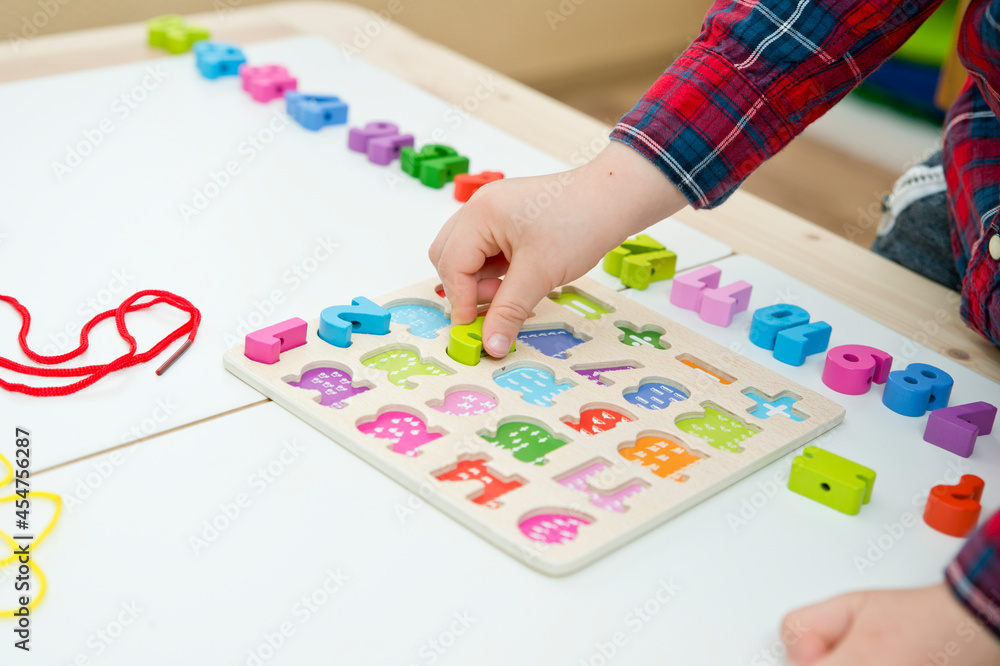 kid learning numbers through game. Sensory activity with wooden numbers and shoe laces. Educations at home, pre-school education, Montessori methodology. sequence of numbers, arithmetic problems. kid learning numbers through game. Sensory activity with wooden numbers and shoe laces. Educations at home, pre-school education, Montessori methodology. sequence of numbers, arithmetic problems.