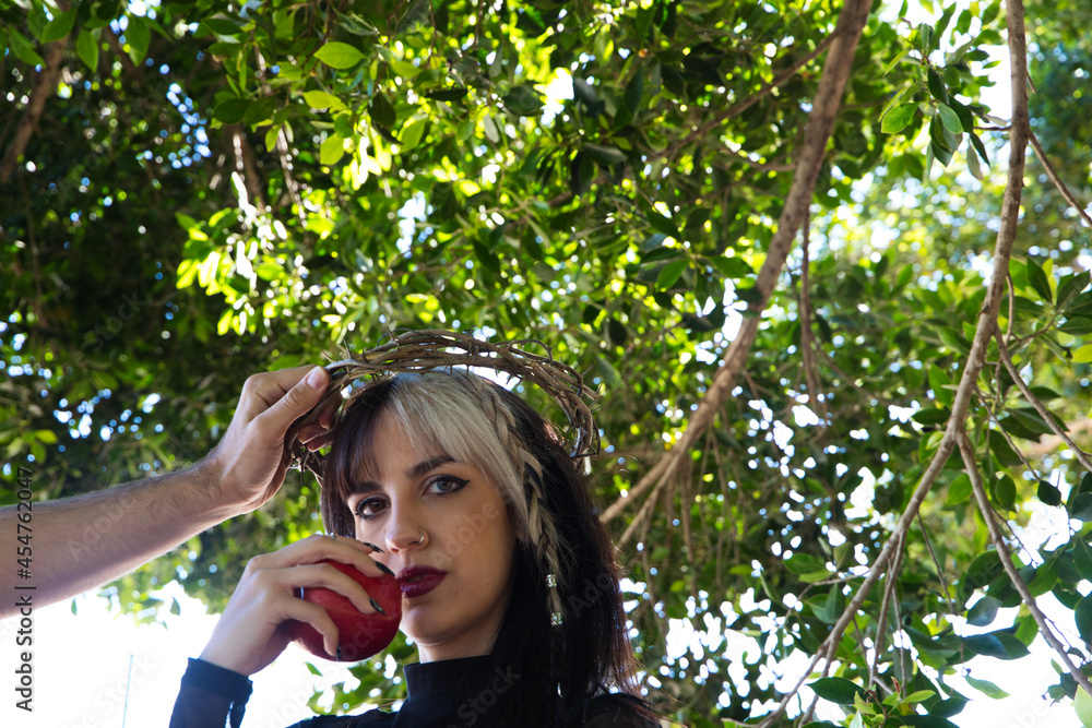 punky girl with blonde and brunette hair holding a red apple in her hands, the girl wears a crown of thorns like christ on her head. The girl is a witch from the fairy tale. punky girl with blonde and brunette hair holding a red apple in her hands, the girl wears a crown of thorns like christ on her head. The girl is a witch from the fairy tale.