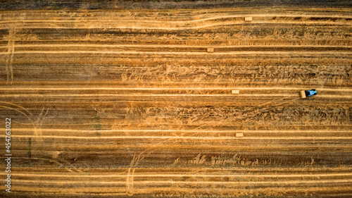 Photography Tractor working on a farm and collecting hale straw bales.