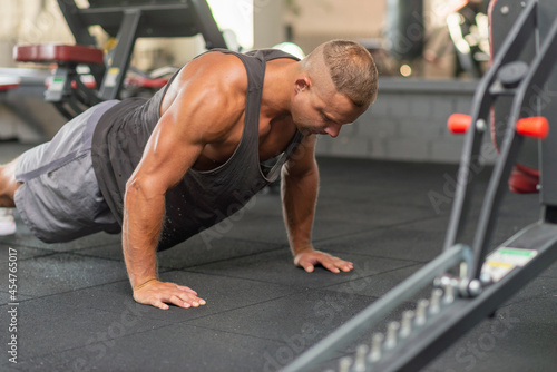 Sport young athletic man doing push-up. Muscular and strong guy exercising at a gym.Strength and motivation concept.