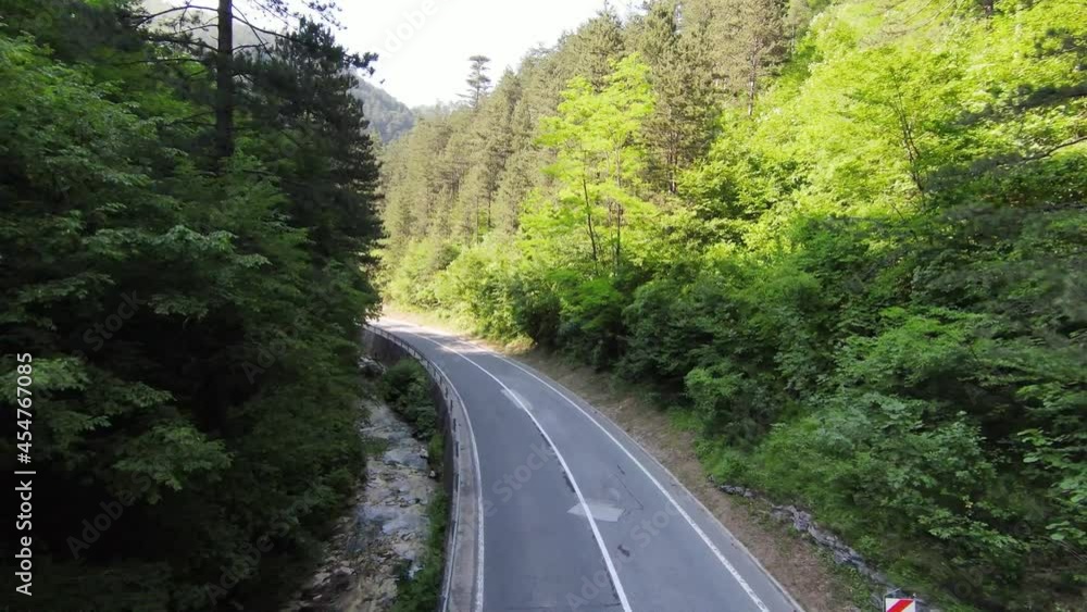 Extreme flight over treetops in the forest and curvy country road. Aerial shot on fpv sport drone sunny landscape with mountain hilly terrain and country road. Dynamic cinematic view. Extreme flight over treetops in the forest and curvy country road. Aerial shot on fpv sport drone sunny landscape with mountain hilly terrain and country road. Dynamic cinematic view.