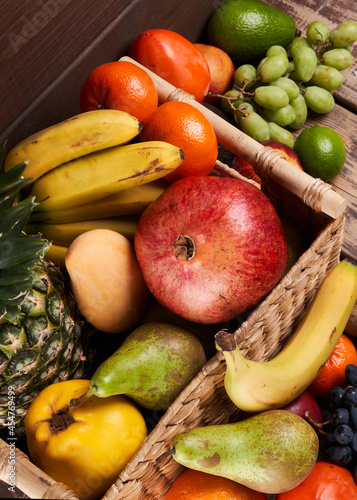 Fototapeta Naklejka Na Ścianę i Meble -  Mix of fresh juicy colorful exotic tropical fruits in basket on wooden background top view