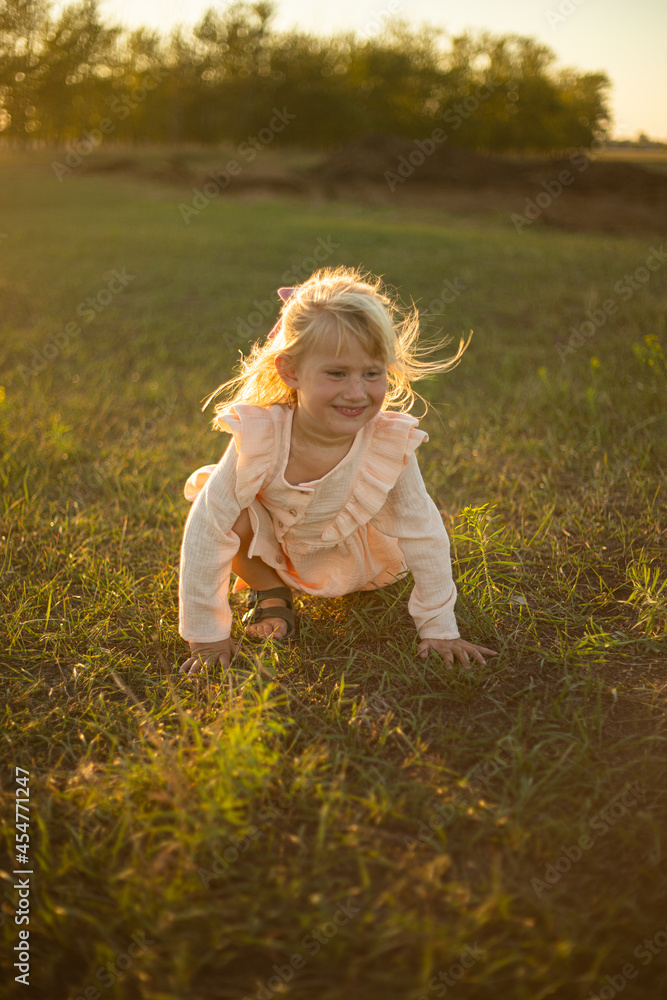 A girl with long hair plays and runs in the rays of the setting sun in a pink dress A girl with long hair plays and runs in the rays of the setting sun in a pink dress