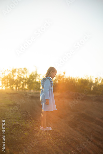 Girl with long hair in the rays of the setting sun in a blue dress © Ева-Мария Фрей