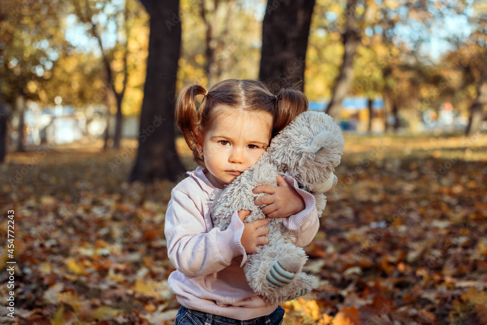 Cute toddler baby girl with soft toy playing outdoors in fall park. Little girl in the autumn park. Fall activities for toddlers. Cute toddler baby girl with soft toy playing outdoors in fall park. Little girl in the autumn park. Fall activities for toddlers.