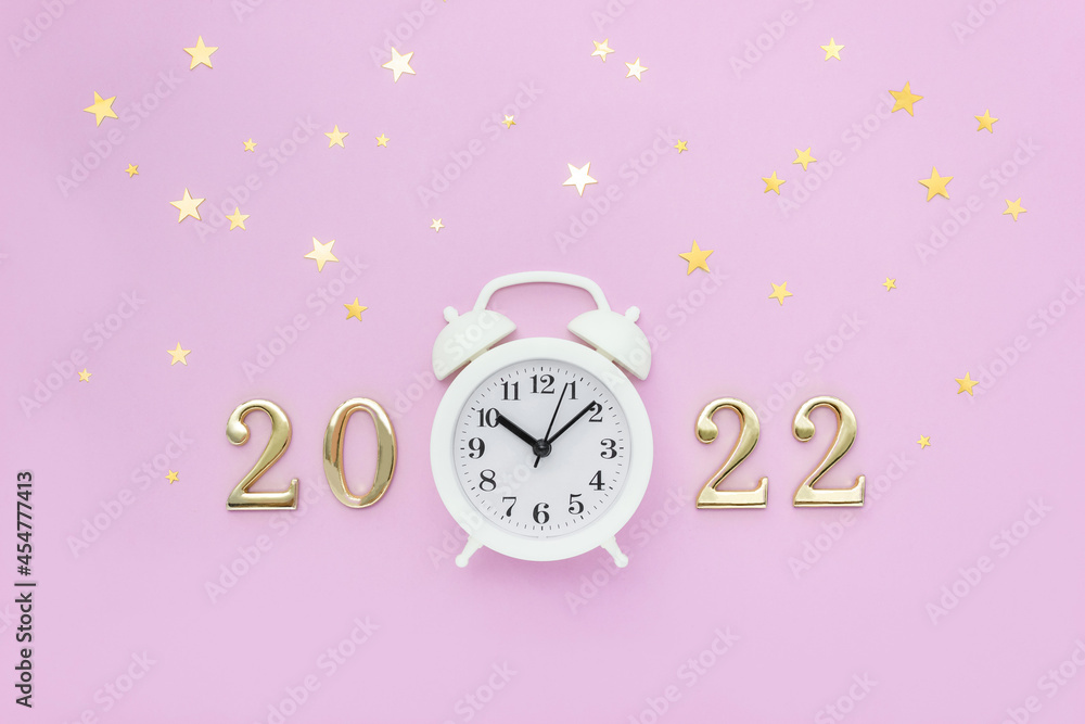 Alarm clock and numbers 2022 are decorated with golden stars confetti. Minimal concept of celebrating Christmas and New Year. Top view, flat lay Alarm clock and numbers 2022 are decorated with golden stars confetti. Minimal concept of celebrating Christmas and New Year. Top view, flat lay