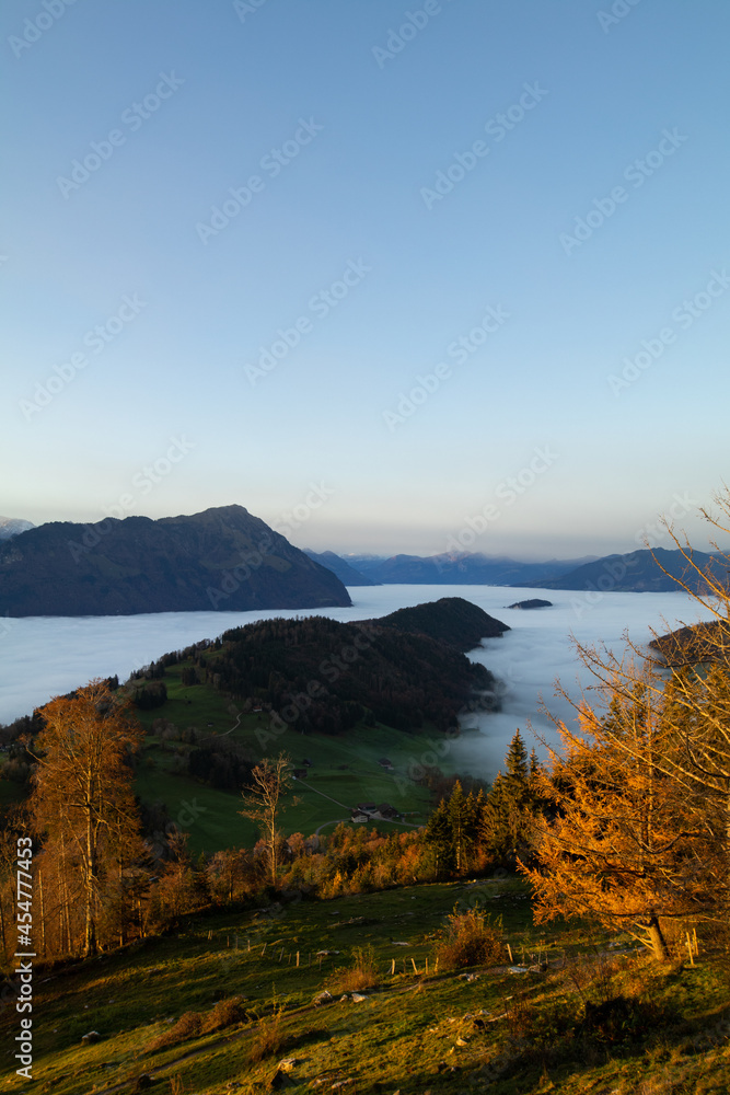 Amazing morning view over the beautiful Lake Lucerne. Epic sunset in the heart of Switzerland. Wonderful scenery with the majestic fog and the swiss alps in the background.