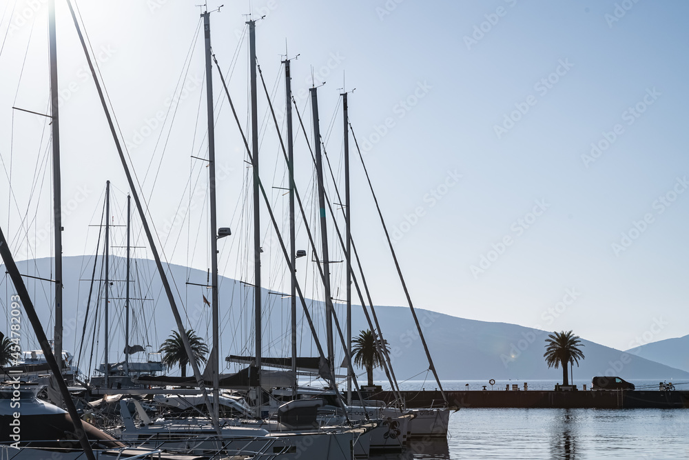 Tivat, Montenegro - October 12, 2019: Light cool haze over the marina. View of yachts, boats, mountains and water. The car rides on a wooden pontoon