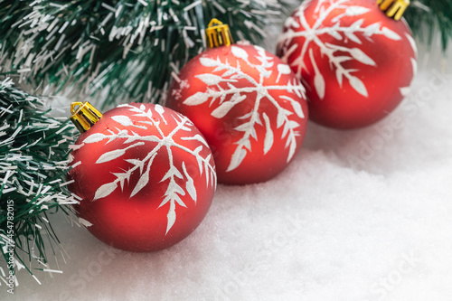 green garland and three red christmas tree ball in snow photo