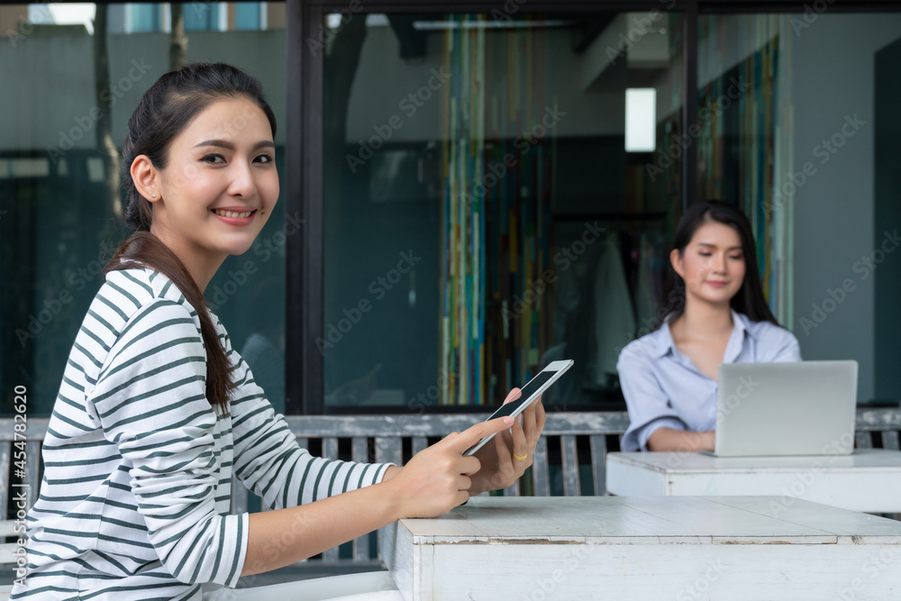 Asian enterpreneur women using tablet while sitting in garden Asian enterpreneur women using tablet while sitting in garden