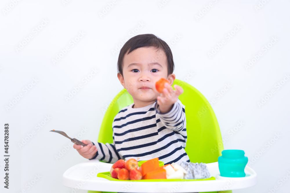 Happy Asian baby sitting in a children chair with fruit, healthy food concept. Happy Asian baby sitting in a children chair with fruit, healthy food concept.