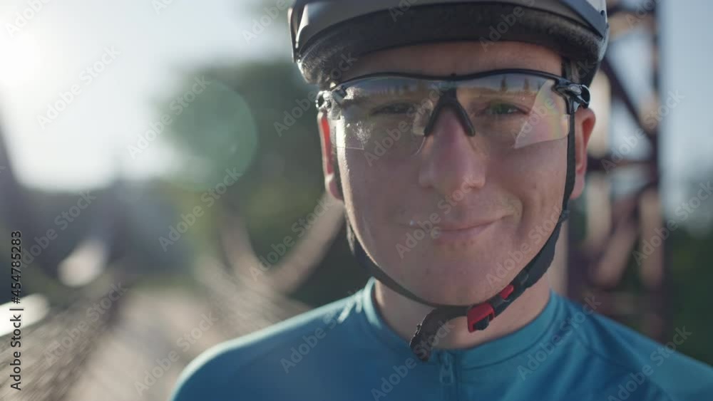Portrait of a young male cyclist. Сlose-up of a man on a sunny day against the background of nature and the bridge Portrait of a young male cyclist. Сlose-up of a man on a sunny day against the background of nature and the bridge