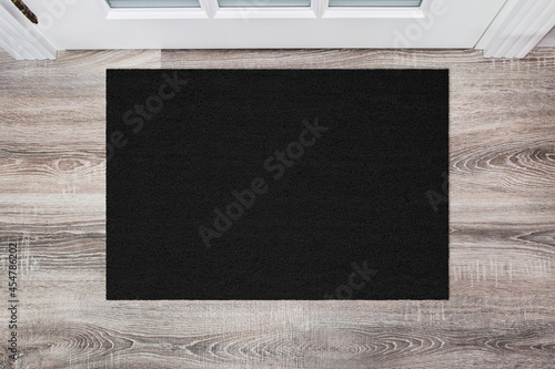 Black Coir Doormat on wooden floor in front of the door. Product mockup photo