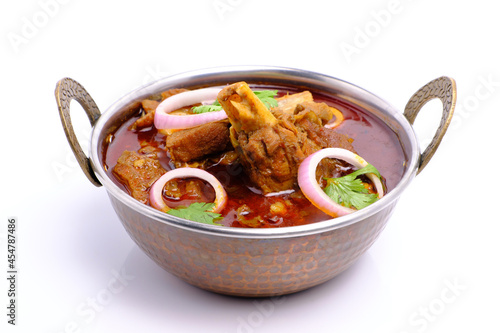 Indian style mutton curry in a copper brass bowl on white background photo