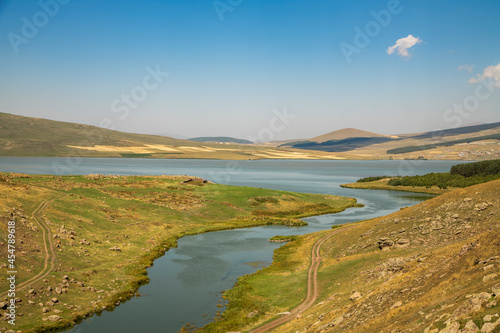 Beautiful landscape. Yellow hills mountains and small lake and river under blue sky.