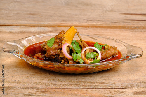 Mutton curry or meat dish in glass bowl on wooden background