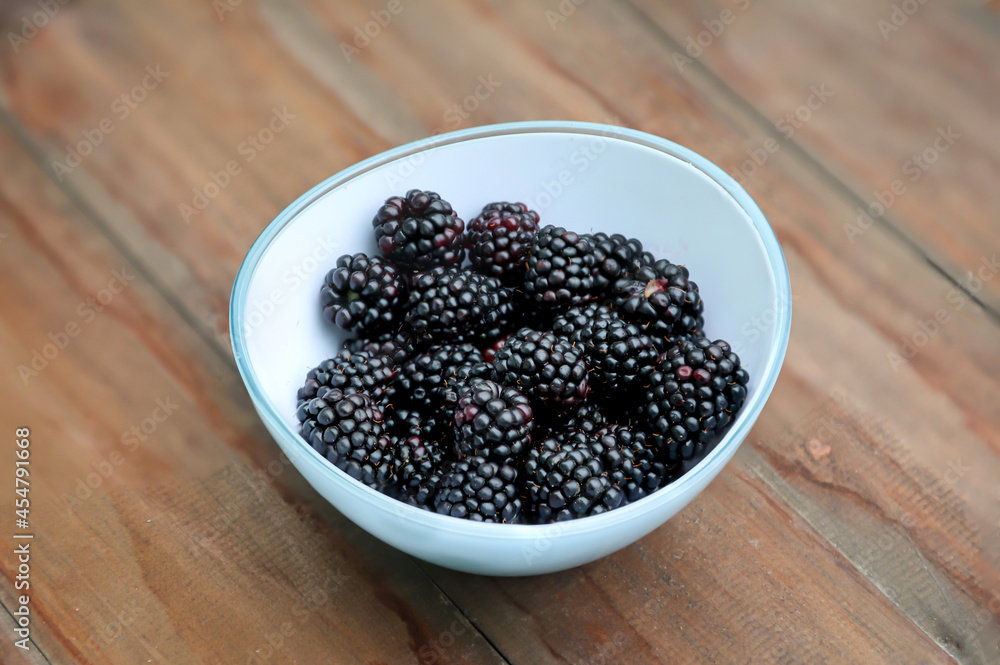 Eine Schale mit reifen und gewaschenen Brombeeren auf einem Holztisch. Eine Schale mit reifen und gewaschenen Brombeeren auf einem Holztisch.