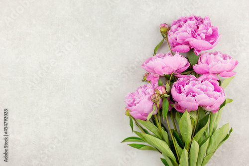 Pink peonies flowers on light gray concrete background. Valentine's, womens, mothers day, easter, birthday or wedding, spring holiday flat lay. Top view. Copy space.