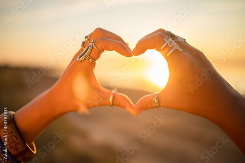 Female hands touch the sun. Hippie woman hands with silver rings at sunset. Indie boho vibes and bohemian style  photo