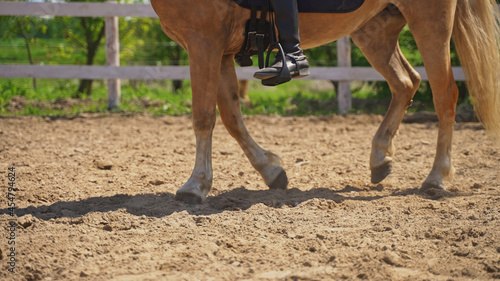 a person rides a light brown horse on the ground near a wooden fence. High-quality photo
