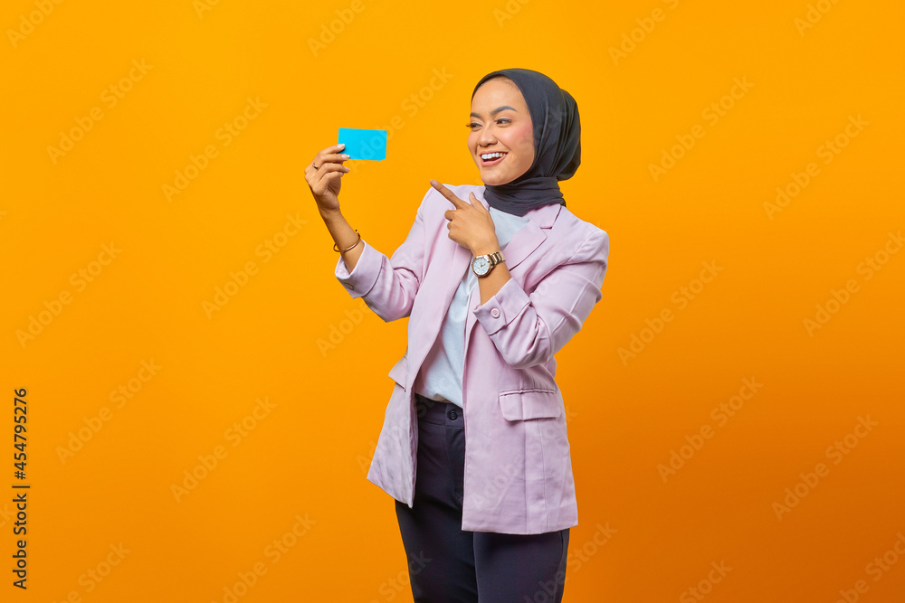 Smiling Asian woman show gesturing finger blank card over yellow backgroundpayment, credit, credit card, card Smiling Asian woman show gesturing finger blank card over yellow backgroundpayment, credit, credit card, card