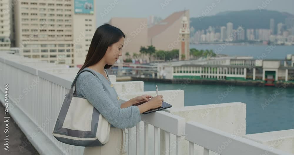 Woman use digital pen on tablet in city of Hong Kong Woman use digital pen on tablet in city of Hong Kong