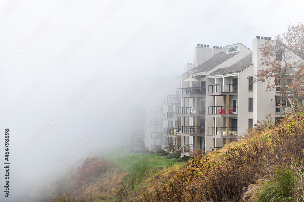Wintergreen, Virginia in morning fog mist with autumn fall foliage trees by apartment condo building balconies at ski resort town village