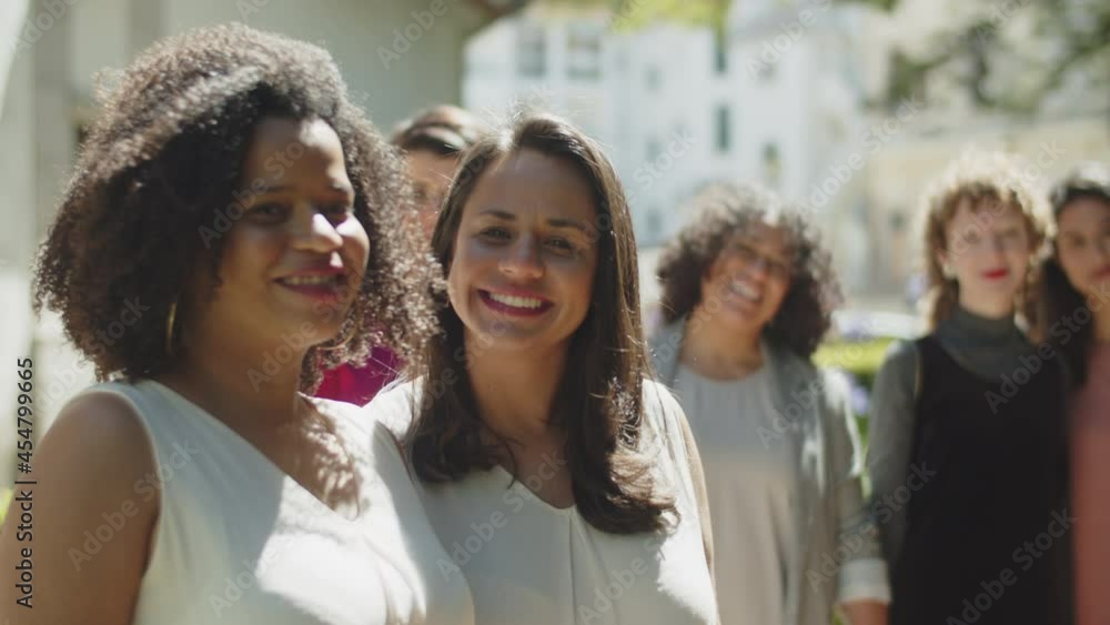 African-American lesbian pair kissing on their wedding day. Medium shot of brides in white dresses posing for camera with their friends, waving hands and smiling. Photoshoot, LGBT wedding concept African-American lesbian pair kissing on their wedding day. Medium shot of brides in white dresses posing for camera with their friends, waving hands and smiling. Photoshoot, LGBT wedding concept