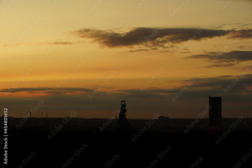 Sunset or dawn in yellow over a small town, the silhouette of city buildings in dawn or sunset light.