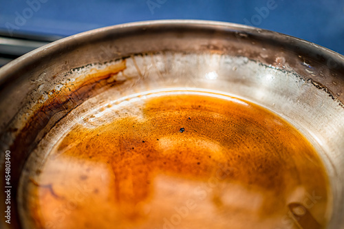 Burnt clarified butter ghee in dirty stainless steel frying pan due to high heat macro closeup