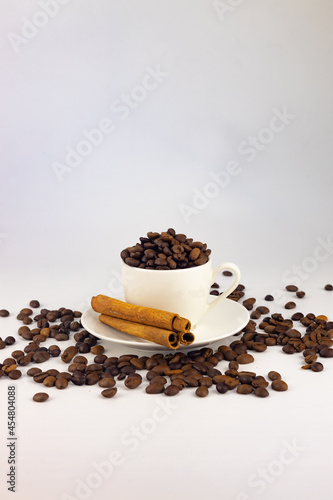 Coffee cup and coffee beans with cinnamon sticks on white background
