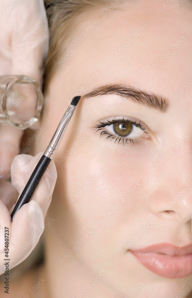 Young woman correcting eyebrow shape with brush, closeup