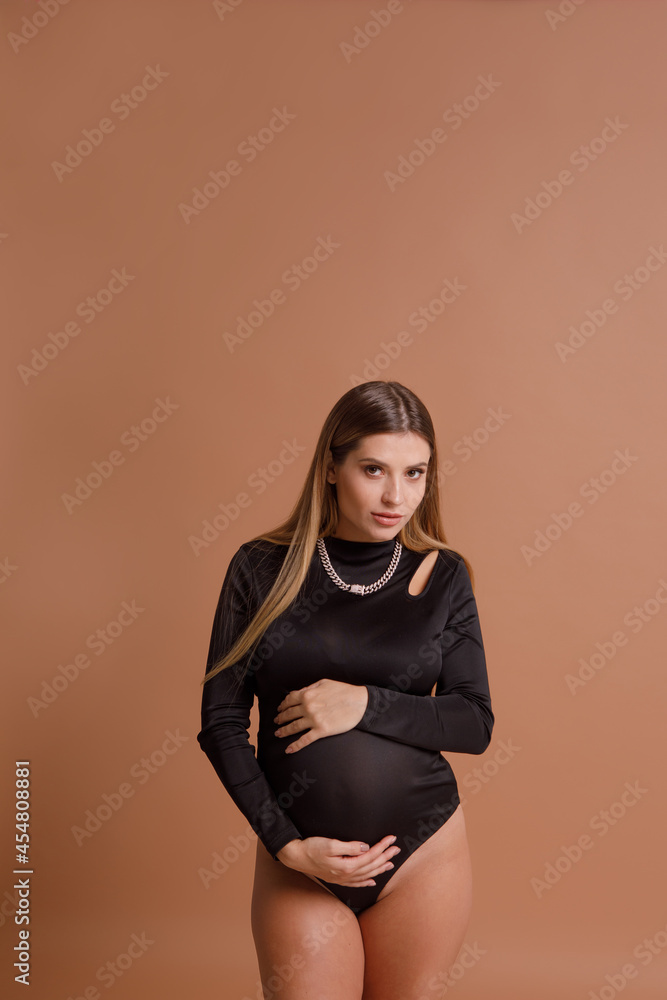 Obraz premium Beautiful pregnant young woman in studio on beige background