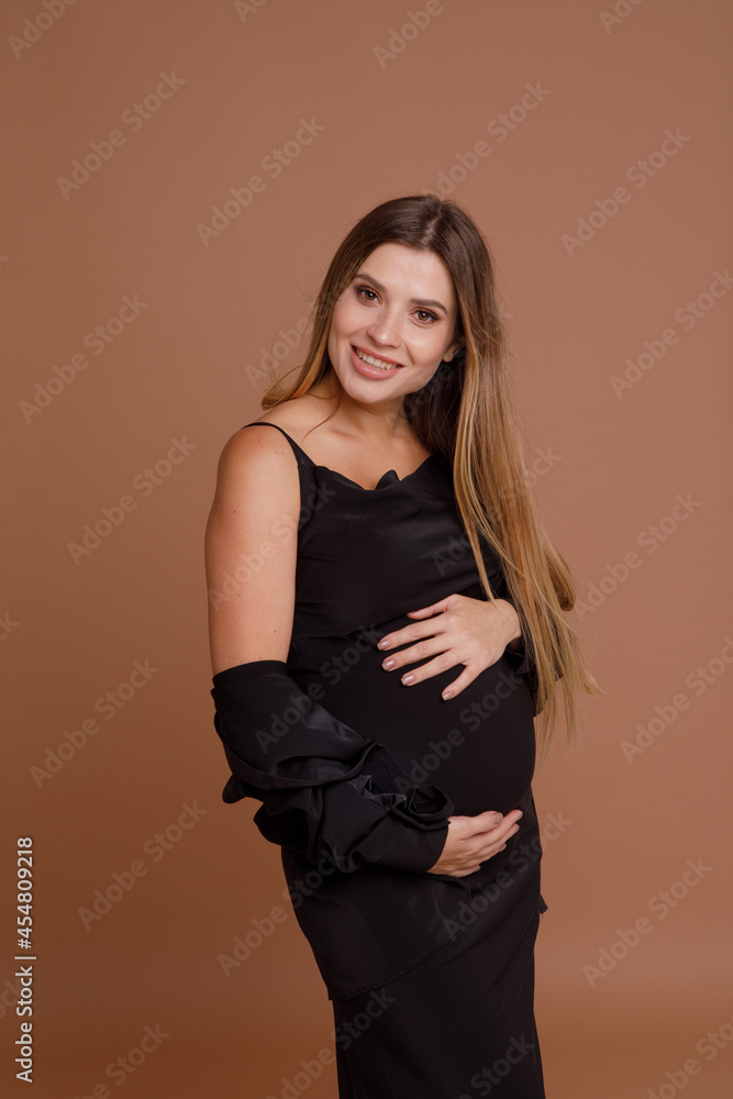 Beautiful pregnant young woman in studio on beige background Beautiful pregnant young woman in studio on beige background