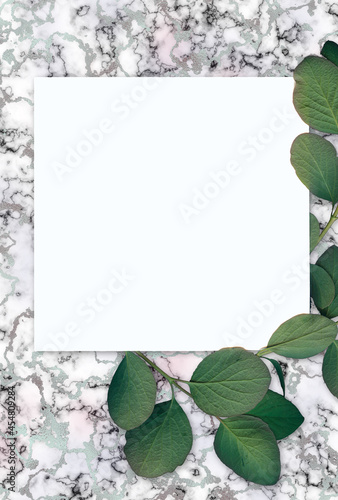Fresh spring green leaves on light marble background with silver glitter. Summer concept, flat lay, top view.