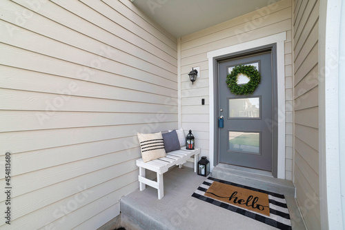 Small front porch with white bench and gray front door