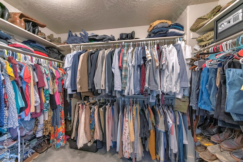 Full walk in closet with clothes hanging on the clothing rods photo