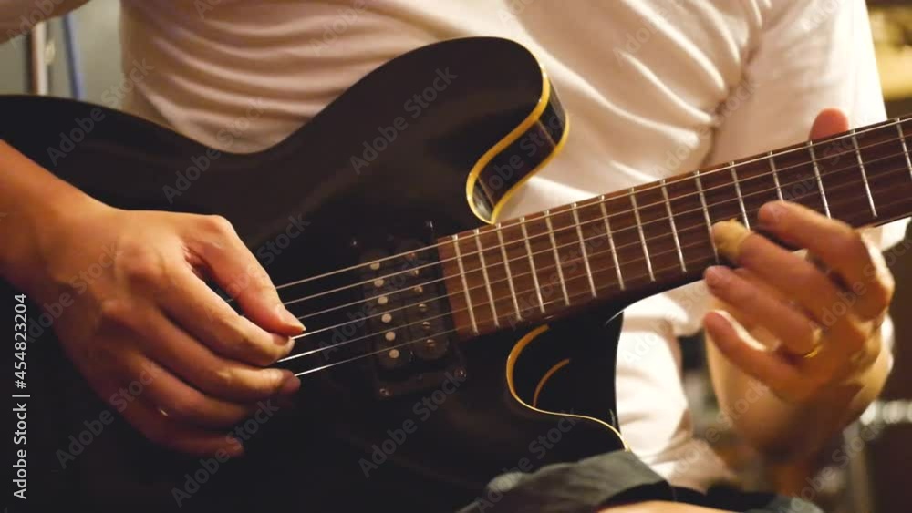 Asian Man With Manicured Hands Playing Black Guitar Asian Man With Manicured Hands Playing Black Guitar