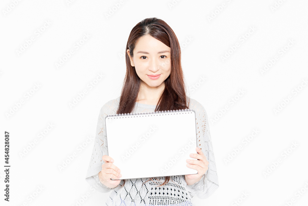小さいスケッチブックを持って案内をするカジュアルな服を着ている女性 小さいスケッチブックを持って案内をするカジュアルな服を着ている女性