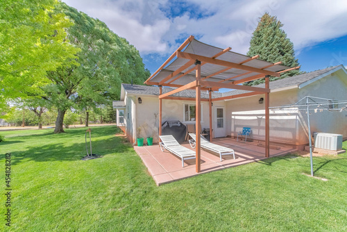 Outdoor patio of a house with two lounge chairs under the shade photo