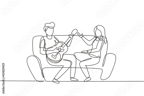 Single one line drawing couple together in love. Boy is playing guitar to his girlfriend in living room on sofa. Girl listen and singing together. Modern continuous line draw design graphic vector photo