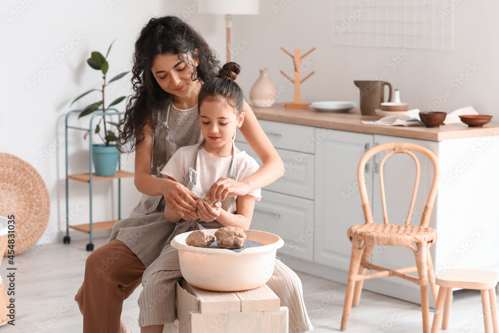 Little girl with her mother making ceramic pot at home Little girl with her mother making ceramic pot at home