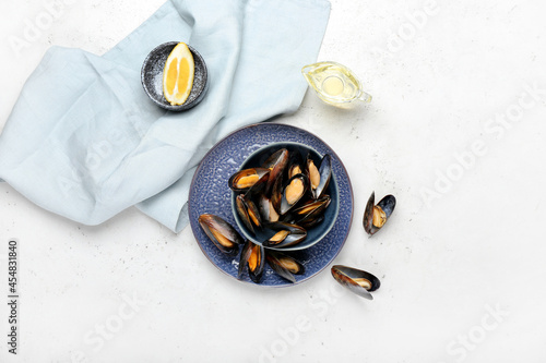 Bowl with tasty mussels on light background